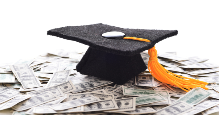 A graduation cap sitting on a pile of money